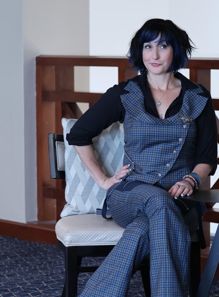 Tricia sitting in a chair wearing a plaid blue outfit she created herself